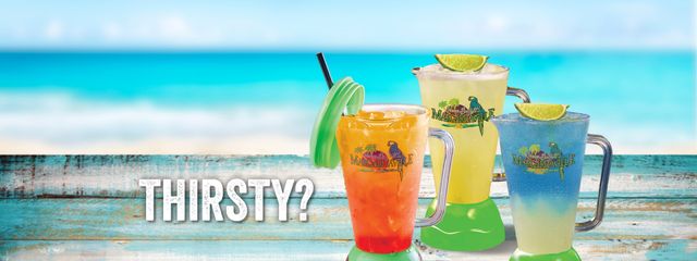 Blender cups with frozen beverages on the beach. Thirsty? Click to view our full beverage and dining menu online.