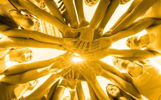 Large group of people putting their hands into the center of a circle