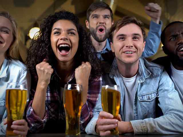  Group of fans cheering while watching a game and enjoying a Landshark Lager
